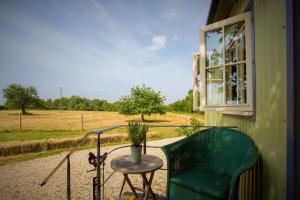 uma cadeira verde num alpendre com uma mesa e uma janela em the abberton shepherds hut em Evesham