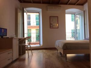 a bedroom with a bed and a desk and two windows at La Dolce Vita in Riomaggiore