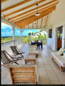 eine Veranda mit Stühlen, einem Tisch und einem Klavier in der Unterkunft Villa Lauréal in Grand-Bourg