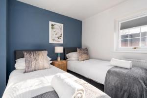 2 camas en una habitación con paredes azules y ventana en Very Close to Manchester Airport and Wythenshawe Hospital - Tailored for Monthly and Long Term Stays en Sale