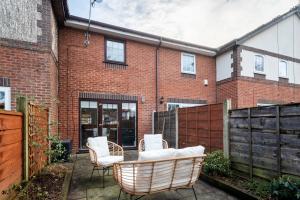 un patio con sillas de mimbre y un edificio de ladrillo en Very Close to Manchester Airport and Wythenshawe Hospital - Tailored for Monthly and Long Term Stays en Sale