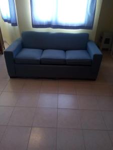 Sofá azul sentado en una habitación con suelo de baldosa en La Costa en Las Grutas