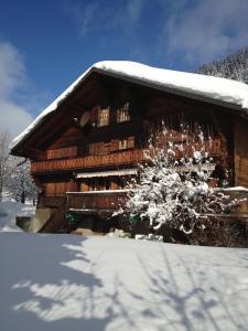 una cabaña de madera con nieve en el costado. en Le Reposoir, en La Comballaz