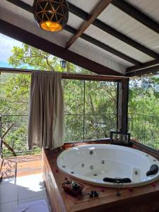 a large bath tub in a room with a large window at Pousada Santa Vila in Serra do Cipo