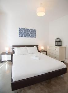 - une chambre avec un grand lit blanc et deux lampes dans l'établissement VBH PENTHOUSE SPINOLA ST. JULIAN'S, à San Ġiljan