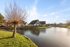 een huis naast een rivier met een boom bij Villa Vermeer in Callantsoog