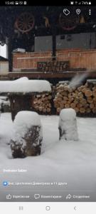 a picture of a snow covered yard with logs at Събевата къща in Sinʼo Bŭrdo