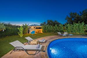 una piscina con tumbonas y sillas alrededor en Romanza Luxury Villa, en Kalamaki