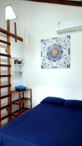 Un dormitorio con una cama azul y una pintura en la pared en Portón Azul, en Montañita