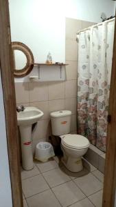łazienka z umywalką toaletową i zasłoną prysznicową w obiekcie Portón Azul w mieście Montañita