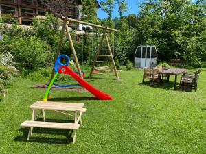 a playground with a slide and a swing at Chalet Tirolia in Kirchdorf in Tirol