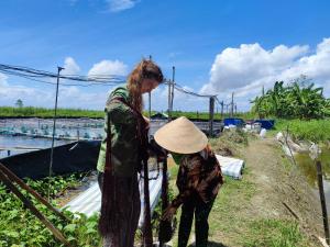 two women are standing next to a fence at Bà Ngoại Homestay in Cà Mau