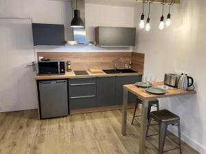 a kitchen with a table and a sink and a microwave at ALP Chartres - Cosy studio au cœur de Chartres avec Parking in Chartres