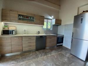 a kitchen with wooden cabinets and a stainless steel refrigerator at Seaside house for 8 close to Olympia & the beach in Levendokhórion