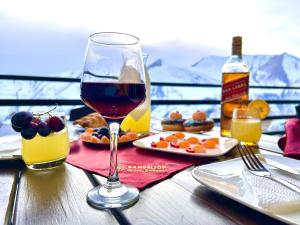 a glass of wine sitting on a table with food at Dandelion Hotel Gudauri in Gudauri
