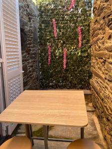 uma mesa de madeira em frente a uma parede com flores cor-de-rosa em Apartamentos Barbosa em Vila Nova de Foz Côa