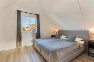 een slaapkamer met een bed en een groot raam bij Villa Vermeer in Callantsoog