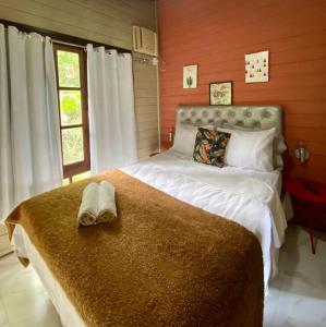 Schlafzimmer mit einem Bett mit weißer Bettwäsche und einem Fenster in der Unterkunft Chalé Ouro Verde in Angra dos Reis