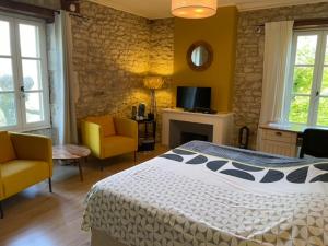 a bedroom with a bed and two chairs and a fireplace at B&B Culinaire La Mouline - adults only in Belvèze