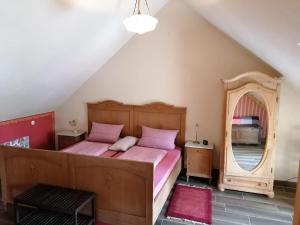 Schlafzimmer mit einem Bett mit rosa Bettwäsche und einem Spiegel in der Unterkunft Ferienwohnungen Bistro Tebecks in Wadern