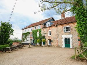 un gran edificio de ladrillo con mesas de picnic delante de él en Springfield, en Fakenham