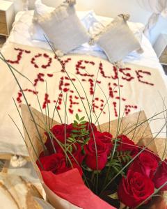 ein Strauß roter Rosen in einer Vase auf einem Bett in der Unterkunft Studio La Boheme Jacuzzi et Terrasse vu sur Pic Saint Loup in Prades-le-Lez