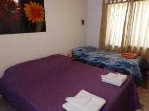 Pokój z dwoma łóżkami i ręcznikami na purpurowym stole w obiekcie Departamento Carrodilla Luján w mieście Lujan de Cuyo