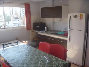 a kitchen with a refrigerator and a table with red chairs at Punta Gesell in Villa Gesell