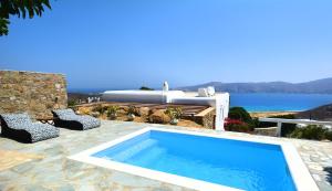 a swimming pool with two chairs and a bath tub at Sea Breeze Mykonos in Panormos Mykonos