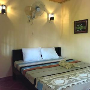 a bed in a room with a fan on the wall at Captain Chim's Guest House in Kep