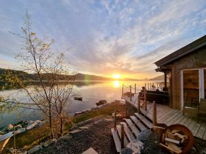 a house with a bench on the shore of a lake at Småstranda Fjord Lodge in Åheim