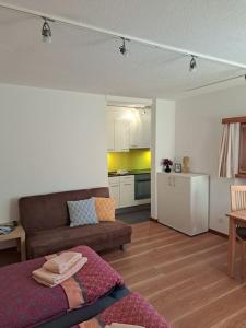 a living room with a couch and a kitchen at Studio Röven in Scuol