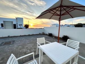 a white table and chairs with an umbrella on a patio at Flip Flops Villa in Yzerfontein