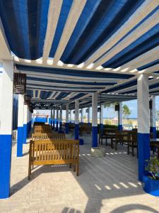 a row of benches sitting under a blue pergola at Al-Ashkhara Beach Resort منتجع شاطئ الأشخرة in Al Ashkharah
