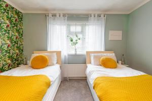 two beds in a small room with yellow cushions at Host & Stay - Gorse Cottage in Mundesley