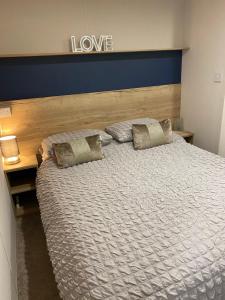 Una cama con dos almohadas y un cartel que dice amor en Dave and Deb's Place Beverley Bay, en Paignton
