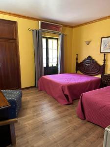 two beds in a room with yellow walls and wooden floors at Quinta do Chao D'Ordem in Vila Nova de Foz Coa