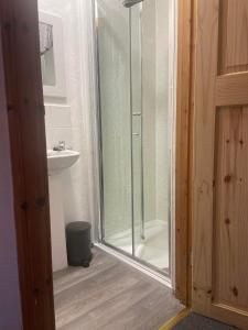 y baño con ducha de cristal y lavabo. en Cosy detached house in central location en Oban