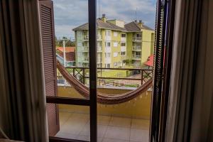 uma vista para uma varanda com uma rede de descanso a partir de uma janela em Condomínio Familiar - Aptos Novos e Completos em Nova Petrópolis