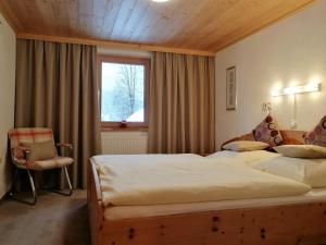 - une chambre avec deux lits, une fenêtre et une chaise dans l'établissement Ferienwohnung Ehrensberger, à Brixen im Thale