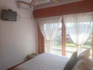 1 dormitorio con 1 cama y una ventana con cortinas blancas en Playa Hermosa a 30mts del mar con 3 dormitorios, en Piriápolis
