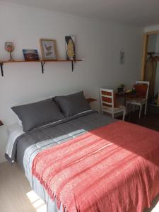 a bedroom with a bed with a red blanket at Mini Casa Rocura Valdivia in Valdivia