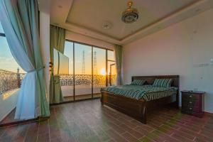 a bedroom with a bed and a large window at COMFORT CHALET & APARTMENTS in Al Ḩadd