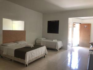 a bedroom with two beds and a flat screen tv at Hotel Xique Xique in Piranhas