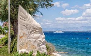 a statue of a face next to the ocean at Apartman Nina in Kali