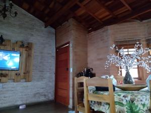 蒙特沃德的住宿－Casa Recanto Beija Flor, Monte Verde，砖墙上的带桌子和电视的用餐室