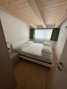 Bett in einem kleinen Zimmer mit Fenster in der Unterkunft Cèsa Sot Bosch in Canazei