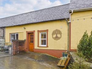 una casa amarilla con una puerta roja y un patio en The Old Boot Room en Llanfynydd