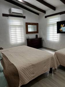 a bedroom with a bed and two windows with white shutters at Casa el Capricho Cancún in Cancún