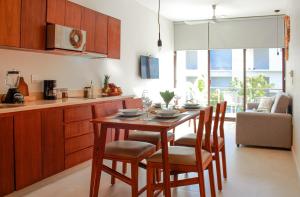 uma cozinha com uma mesa de madeira e cadeiras num quarto em Gama 09 Apartments em Tulum